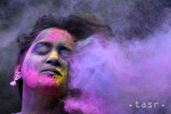 Žena zatvára oči, keď jej do tváre hádžu farebný prášok počas sviatku jari nazývanom holí v Bombaji v utorok 7. marca 2023.